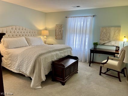 bedroom featuring light colored carpet and visible vents