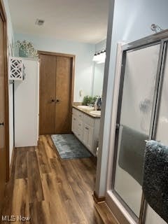 full bath with vanity, wood finished floors, and a stall shower