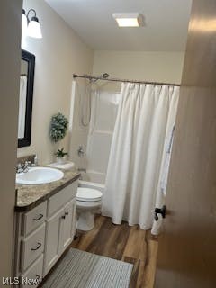 full bathroom with vanity, shower / bath combination with curtain, toilet, and wood finished floors