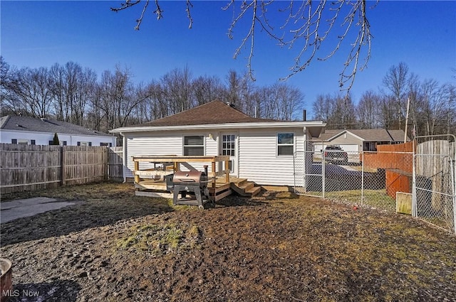 rear view of house featuring a wooden deck, a fenced backyard, and a gate