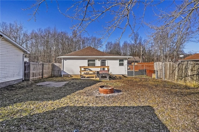 rear view of house with a deck, an outdoor fire pit, a fenced backyard, and a gate