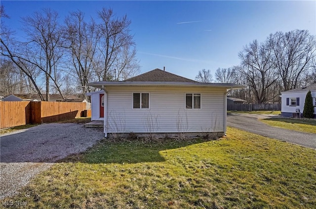 rear view of property with a lawn, driveway, and fence