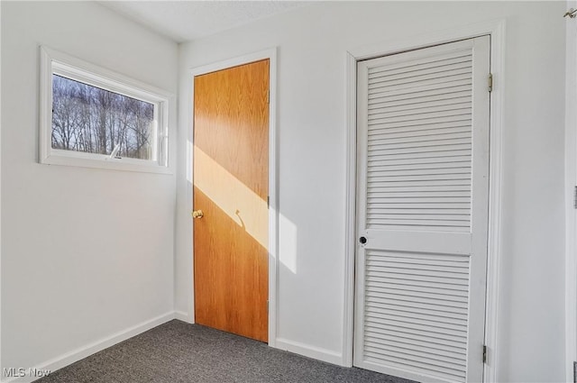 interior space with dark carpet and baseboards