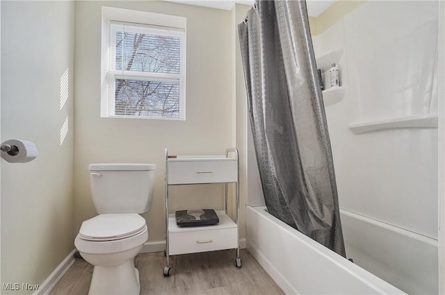 bathroom featuring toilet, shower / tub combo with curtain, baseboards, and wood finished floors