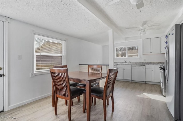 dining room featuring baseboards, a textured ceiling, a ceiling fan, and light wood finished floors