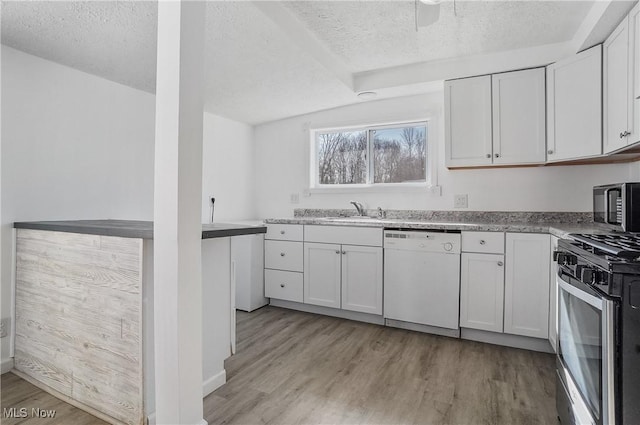 kitchen featuring light wood-style flooring, a sink, a textured ceiling, appliances with stainless steel finishes, and white cabinets