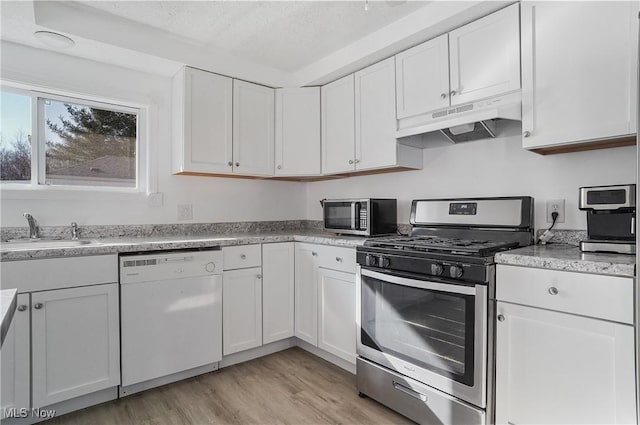 kitchen with a sink, white cabinets, under cabinet range hood, and stainless steel appliances