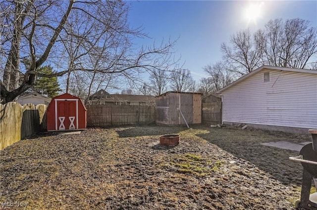 view of yard featuring an outdoor structure, a storage unit, a fenced backyard, and a fire pit