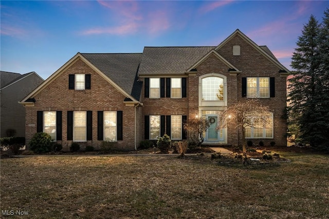 view of front of home with brick siding and a front lawn