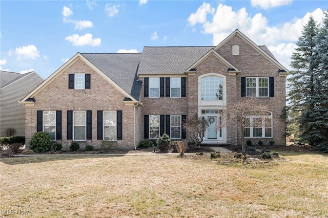 colonial house with a front yard and brick siding