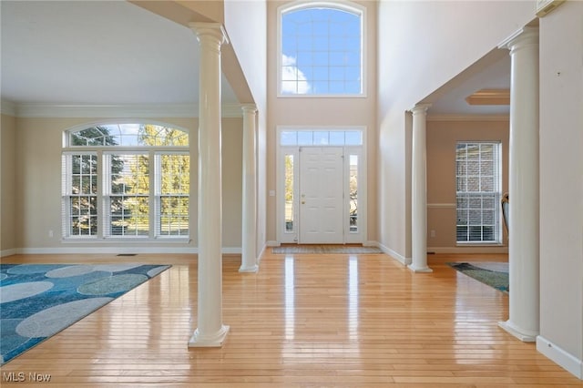 foyer with a healthy amount of sunlight, crown molding, and ornate columns