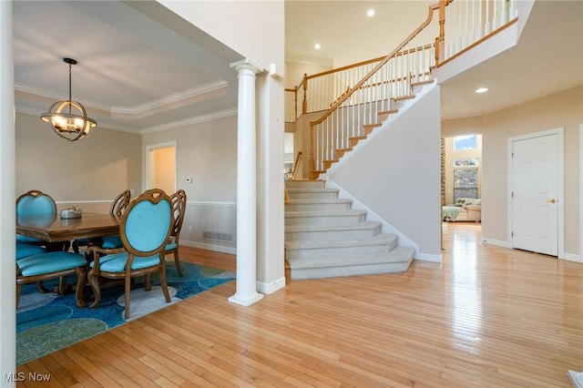 dining space with wood-type flooring, ornamental molding, stairs, and ornate columns