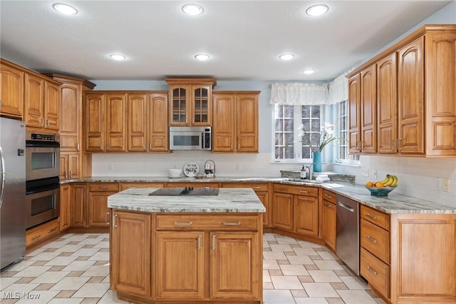 kitchen featuring light stone counters, brown cabinets, appliances with stainless steel finishes, and a center island