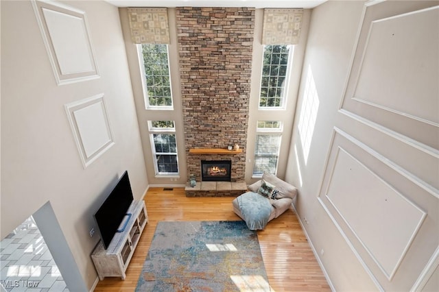 living room featuring a stone fireplace, a healthy amount of sunlight, and light wood finished floors