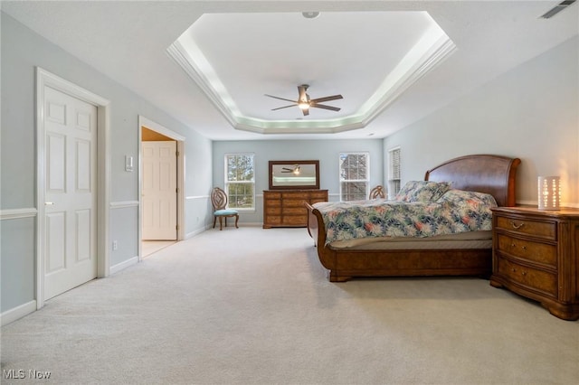 carpeted bedroom featuring visible vents, baseboards, crown molding, a raised ceiling, and ceiling fan