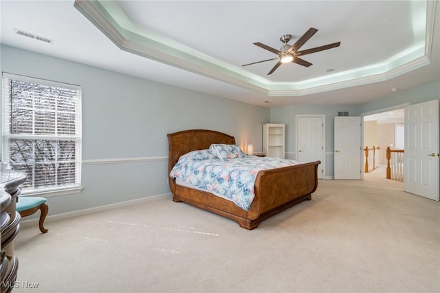 bedroom with a tray ceiling, carpet, visible vents, and baseboards