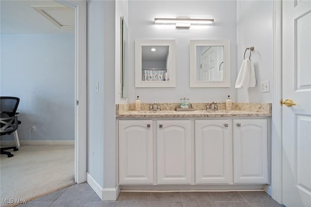 full bath featuring double vanity, baseboards, tile patterned floors, and a sink