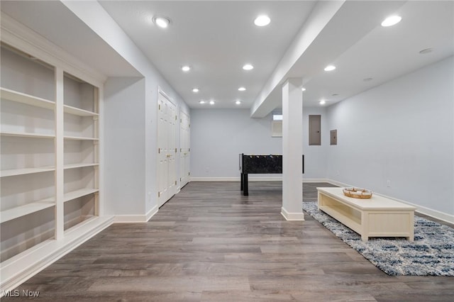 finished below grade area featuring built in shelves, electric panel, wood finished floors, recessed lighting, and baseboards