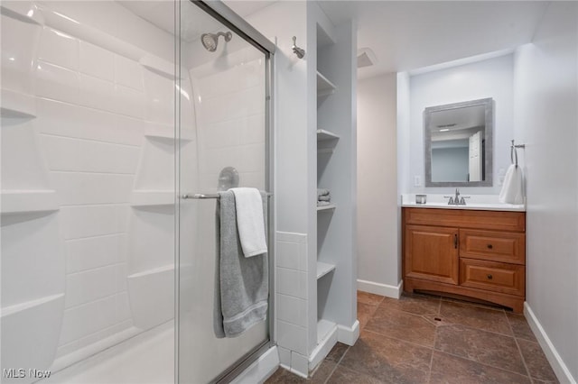 full bath featuring baseboards, vanity, and a shower stall