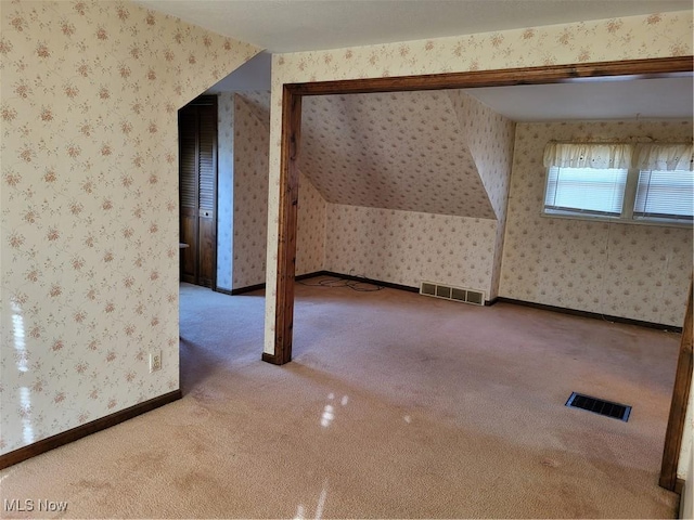 additional living space with wallpapered walls, carpet flooring, baseboards, and visible vents