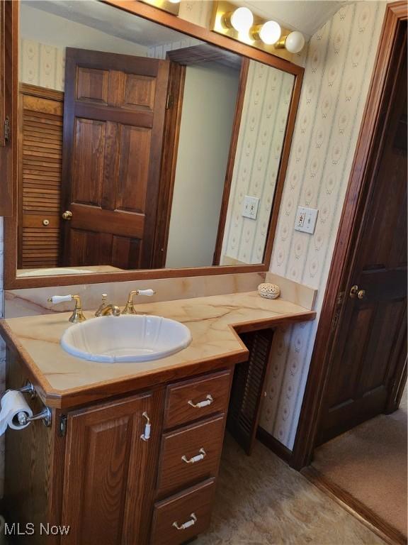 bathroom with vanity and wallpapered walls