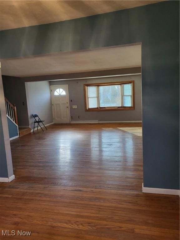 entrance foyer with stairway, a towering ceiling, baseboards, and wood finished floors