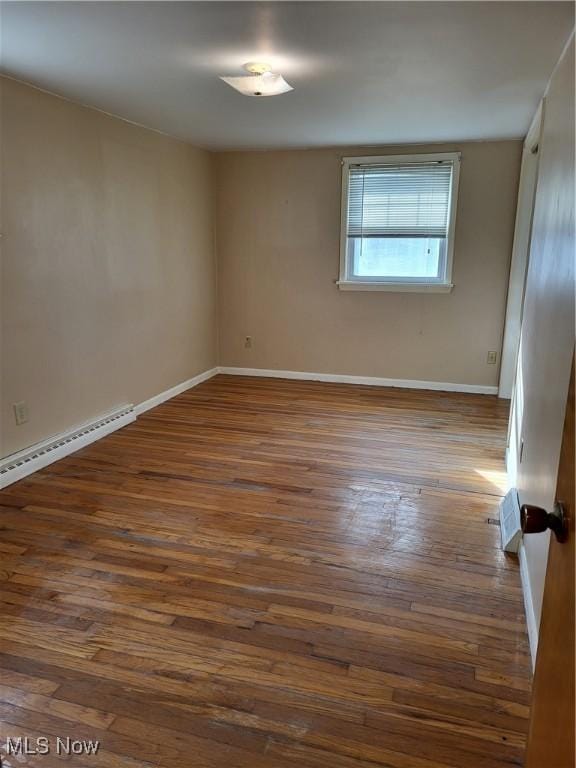 spare room with baseboards, dark wood-style flooring, and baseboard heating