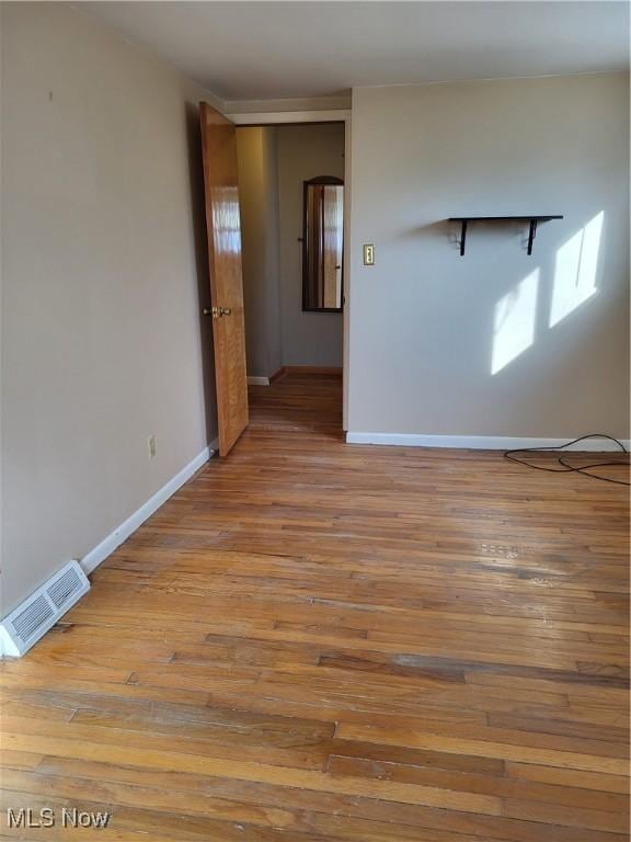 empty room with visible vents, baseboards, and wood finished floors