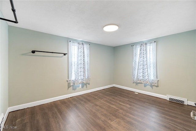 empty room featuring visible vents, baseboards, and wood finished floors