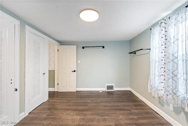 unfurnished bedroom featuring visible vents, baseboards, and dark wood-style floors