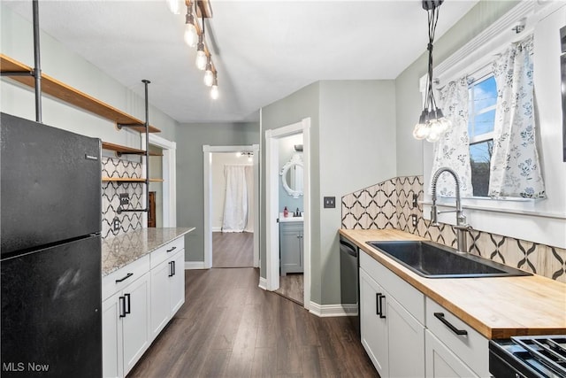 kitchen with decorative backsplash, butcher block counters, black appliances, and a sink