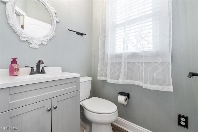 half bath featuring toilet, vanity, and baseboards