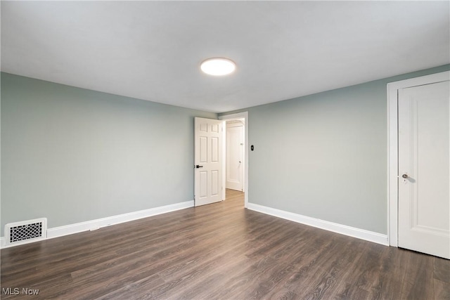 spare room with visible vents, baseboards, and dark wood-style flooring