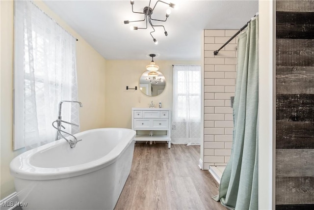 bathroom with vanity, a soaking tub, wood finished floors, and tiled shower