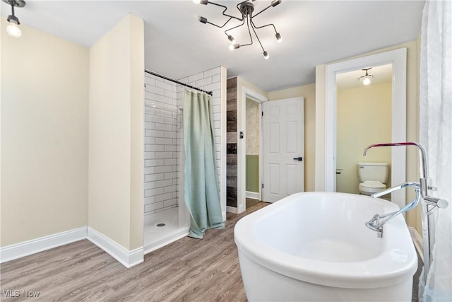 full bathroom with a shower stall, a freestanding tub, wood finished floors, and baseboards