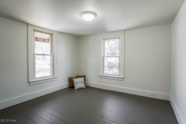 empty room featuring dark wood finished floors, plenty of natural light, and baseboards