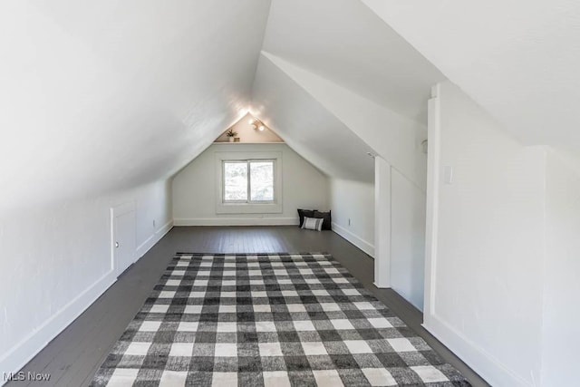 additional living space with baseboards, lofted ceiling, and dark wood-style floors