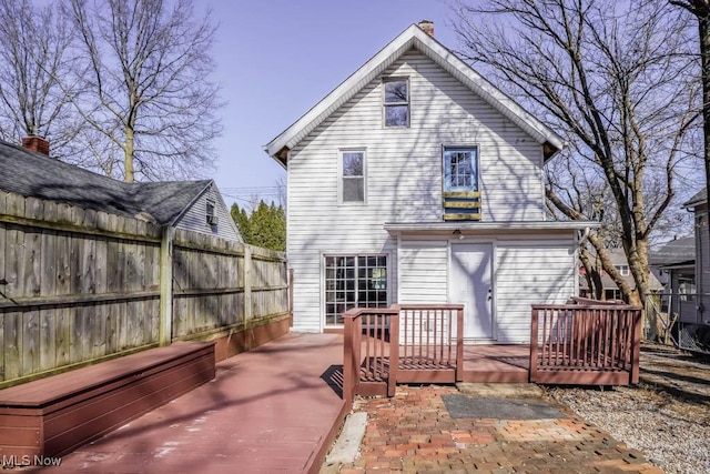 rear view of house featuring a deck and fence