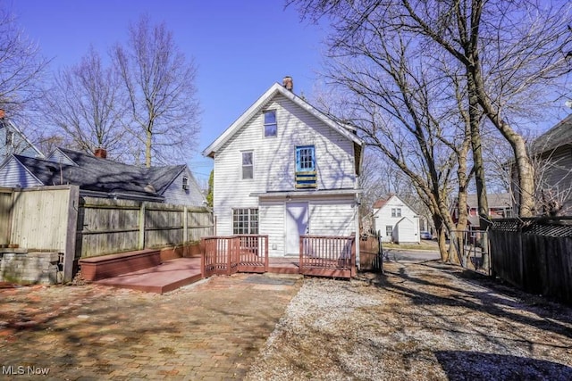 rear view of property with fence, a chimney, and a wooden deck