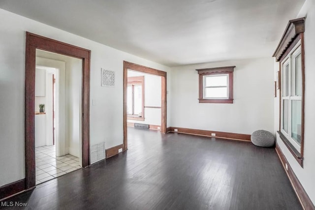 empty room with wood finished floors, visible vents, and baseboards