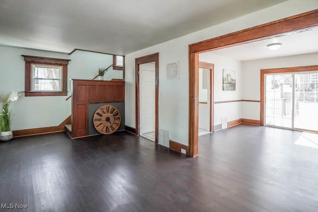 spare room with stairs, dark wood-type flooring, visible vents, and baseboards