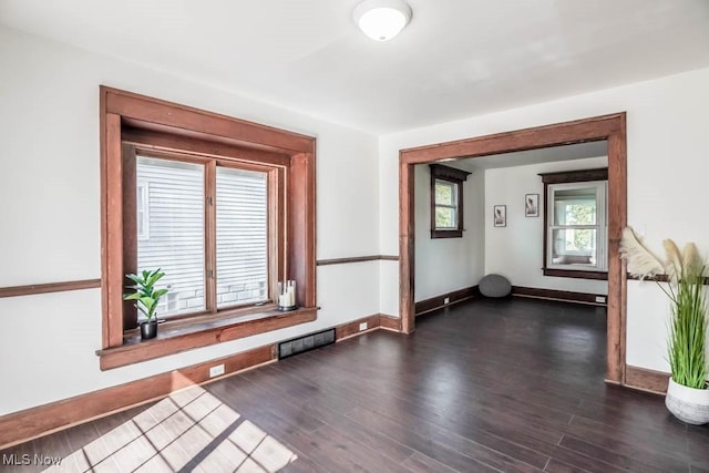 unfurnished room with visible vents, baseboards, and dark wood finished floors