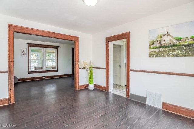 spare room featuring visible vents, baseboards, and wood finished floors