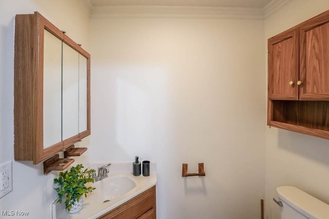 half bathroom featuring toilet, vanity, and crown molding