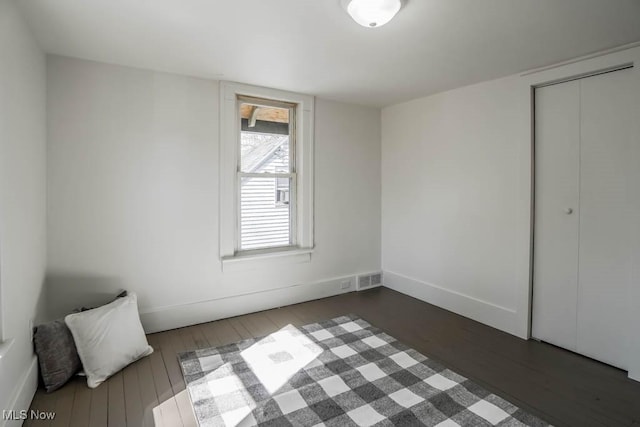 unfurnished bedroom featuring visible vents, baseboards, and dark wood-style floors