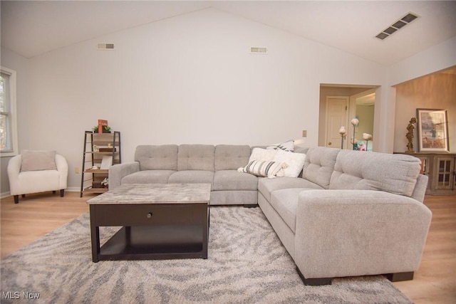 living area with visible vents, light wood-style flooring, and vaulted ceiling