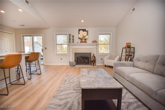 living area featuring vaulted ceiling, plenty of natural light, and visible vents