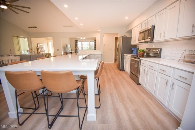 kitchen featuring a spacious island, light wood-style flooring, stainless steel appliances, open floor plan, and backsplash