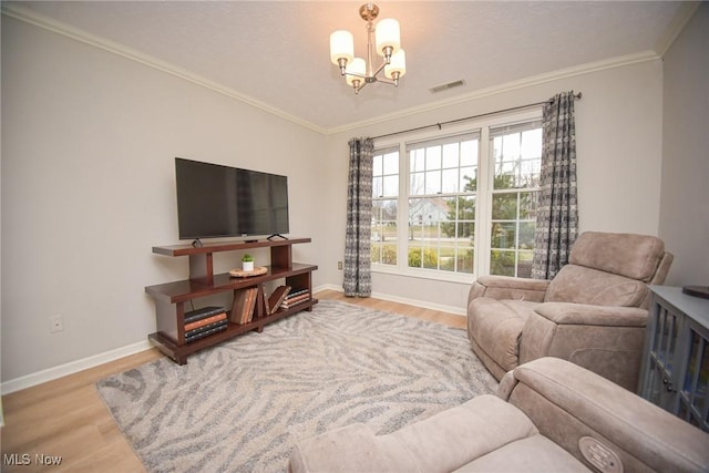 living area with baseboards, a notable chandelier, wood finished floors, and crown molding