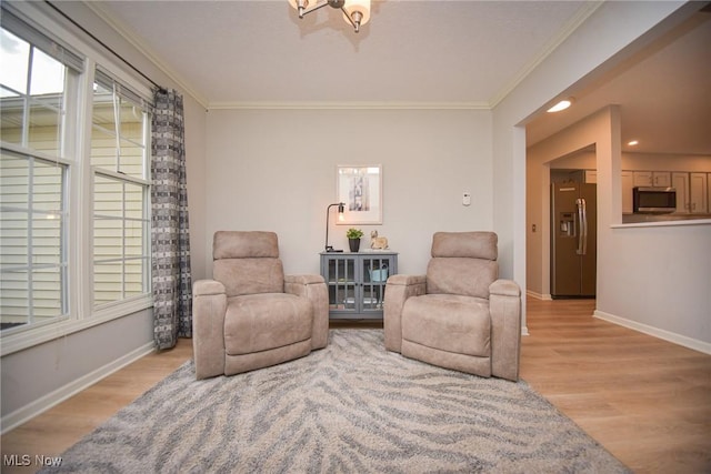 living area featuring baseboards, light wood-style floors, a healthy amount of sunlight, and crown molding